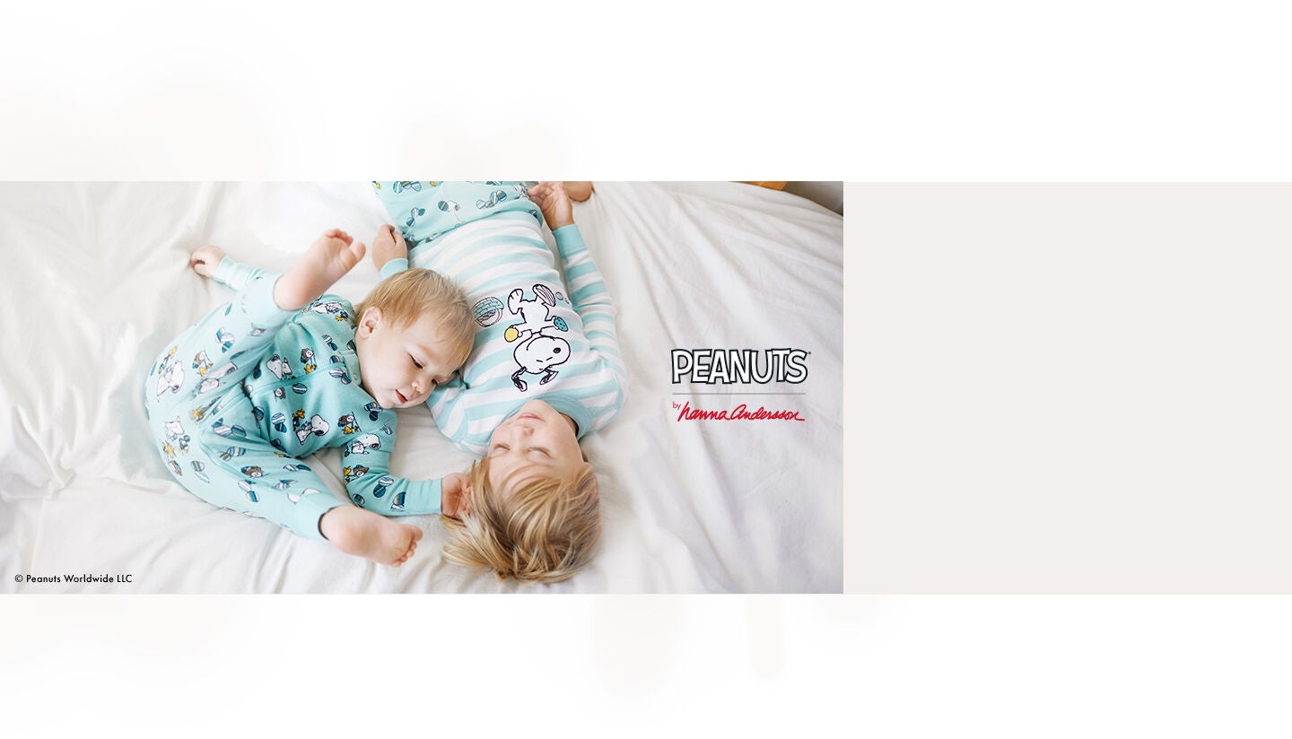 A brother and sister in Snoopy shamrock printed pajamas kissing their younger brother A brother and sister in Snoopy shamrock printed pajamas kissing their younger brother