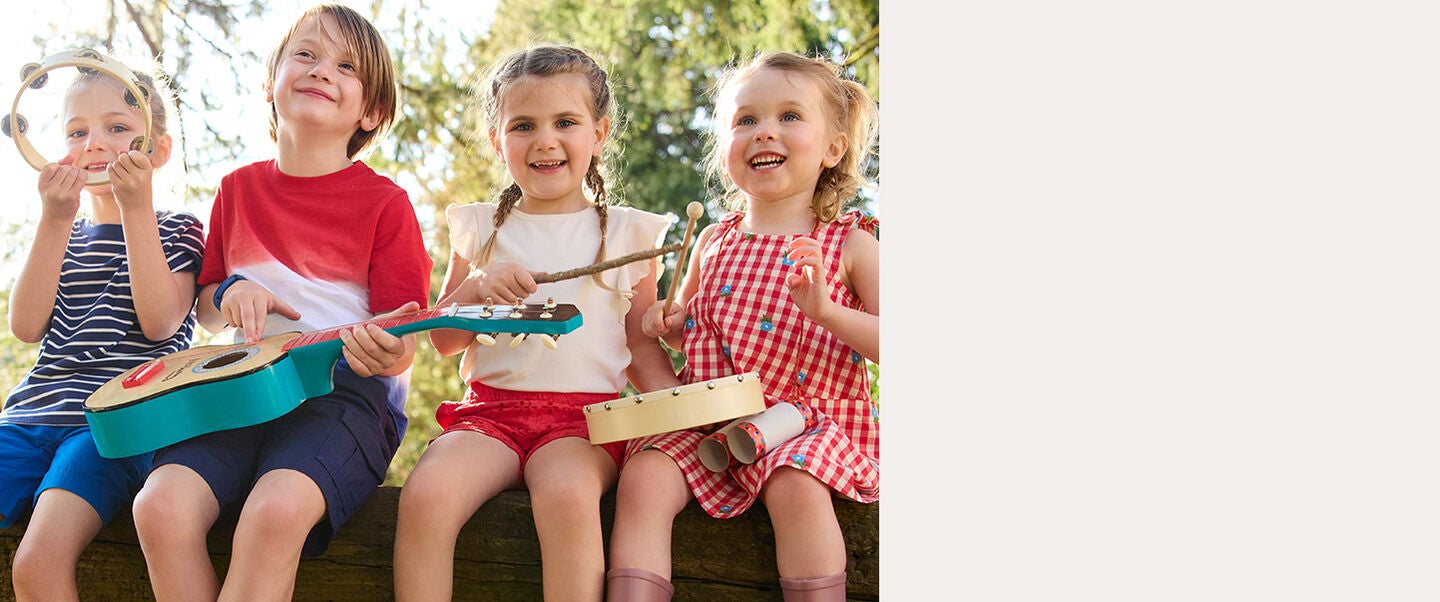 Four kids wearing fun-colored tees and shorts sitting on a log while playing with musical instruments Four kids wearing fun-colored tees and shorts sitting on a log while playing with musical instruments