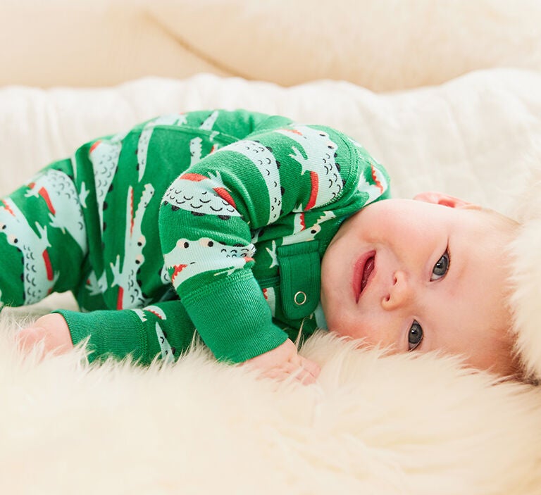 a baby wearing crocodile printed sleeper. Spring new arrivals. shop now.