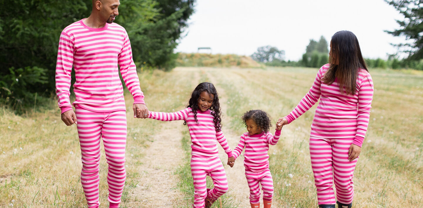 Image of family walking through a field dressed in Hanna Andersson pajamas.