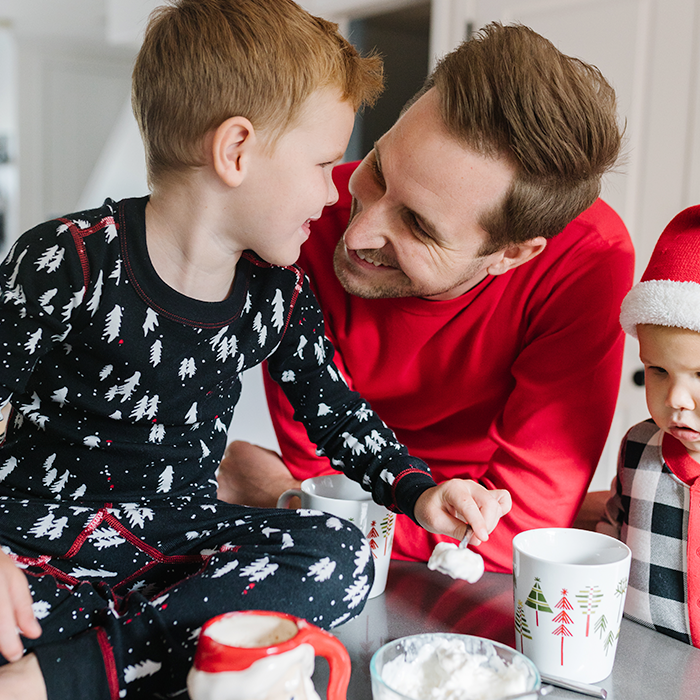 Dad and son drinking hot cocoa in holiday pajamas