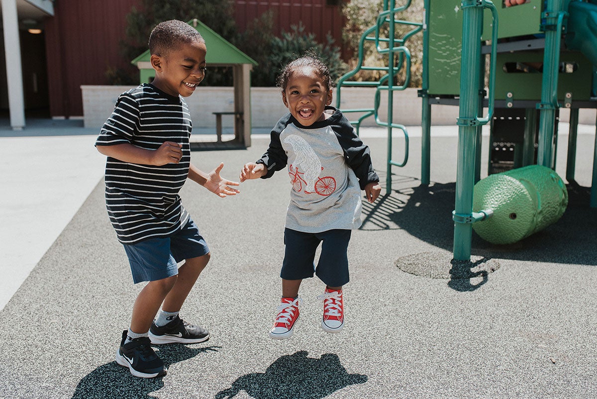 Two smiling kids playing on a playground.