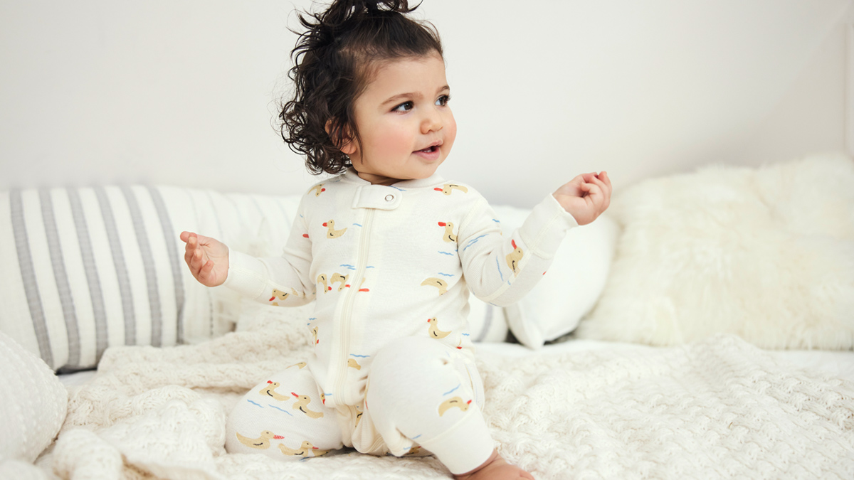 Baby girl in pajamas sitting on bed