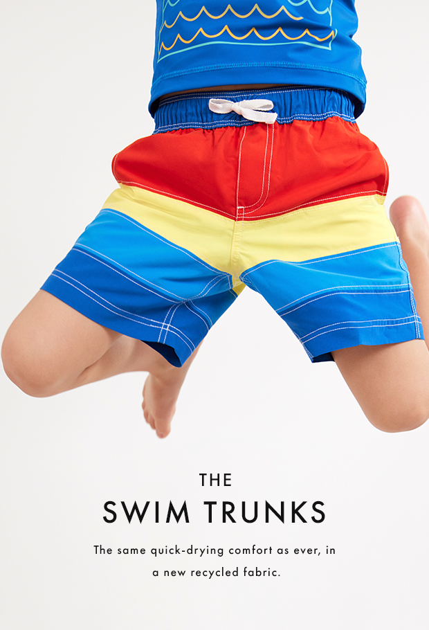 boy jumping in air wearing blue yellow and red swim trunks
