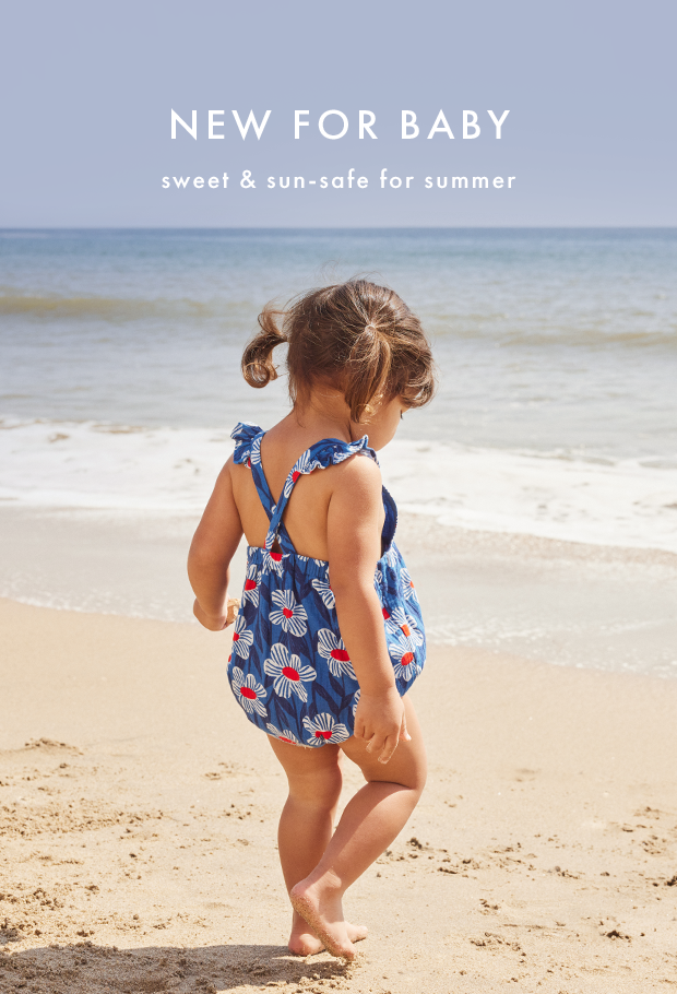 baby walking on the beach wearing a flower romper