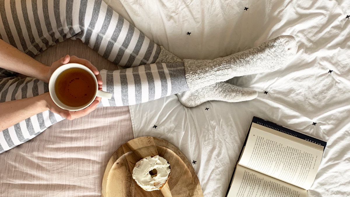 Women is long john pajamas holding coffee and reading