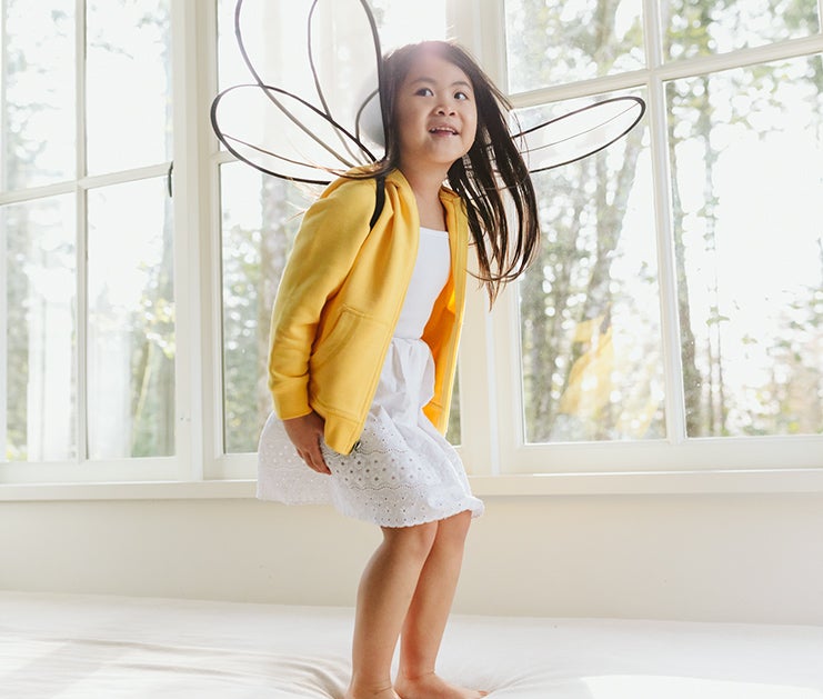 Image of child playing on a bed dressed in Hanna Andersson clothing. Image of child playing on a bed dressed in Hanna Andersson clothing.